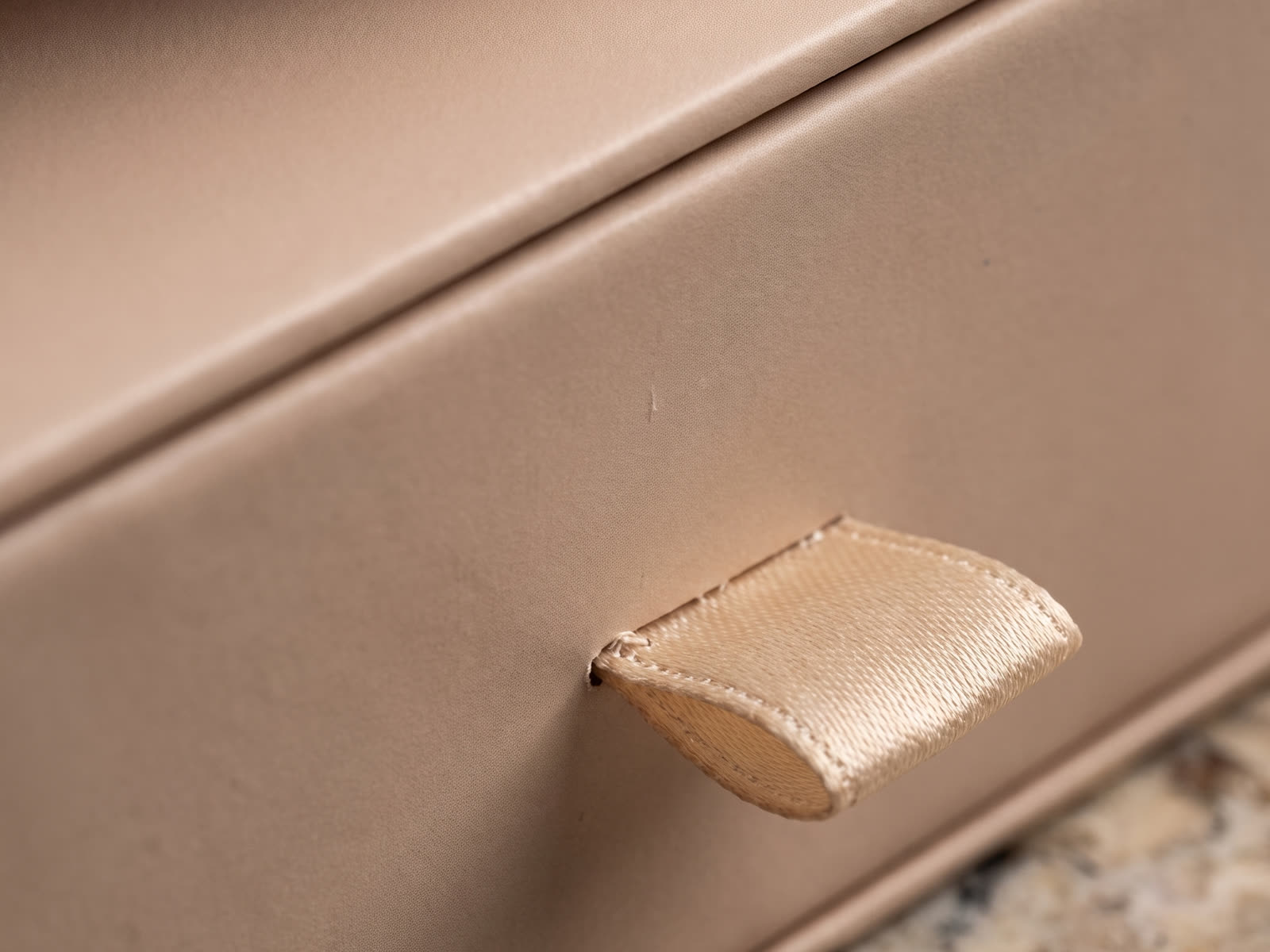 Macro detail of a ribbon pull on a blush-toned rigid box
