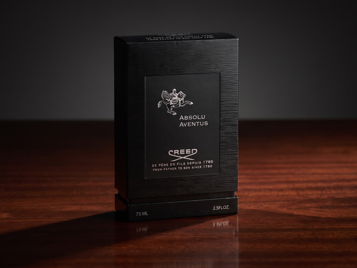 Rigid fragrance box, textured black wrap with foil-stamped crest